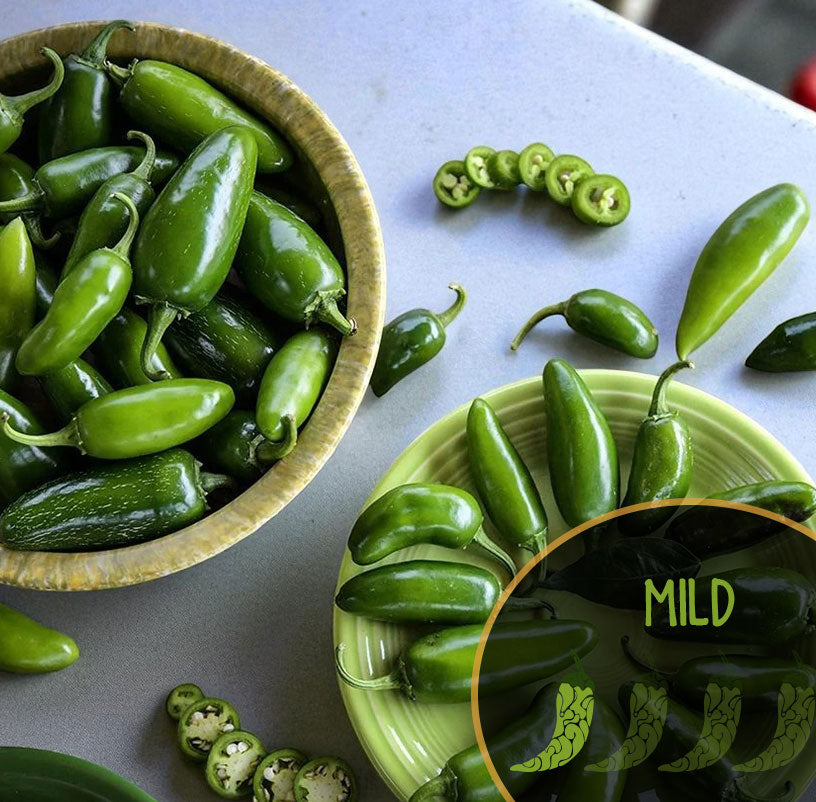 Green Tam jalapeño peppers in a wooden bowl on a white surface with a close-up inset showing 'MILD' text.